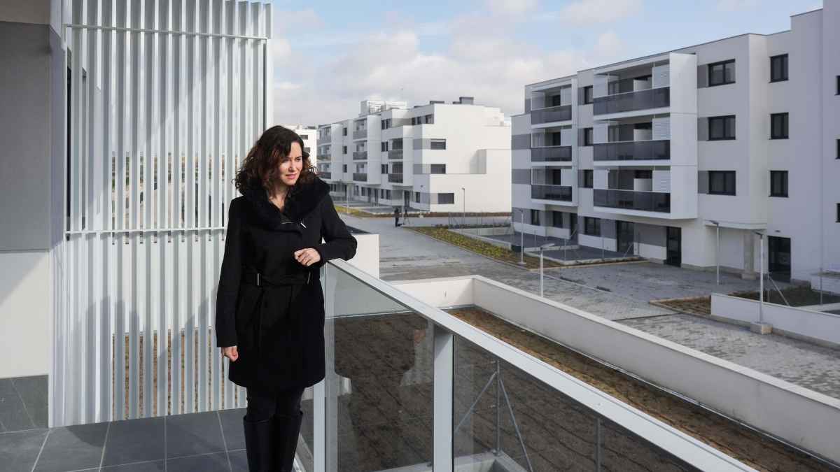 Ayuso en el balcón de una vivienda nueva en Madrid, relacionada con el registro para vivienda protegida.