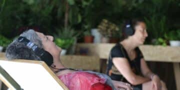 Personas descansando con auriculares en el siestódromo del Refugio Climático del Círculo de Bellas Artes, Madrid.