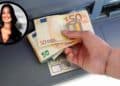 Mano sacando billetes de 50 € de un cajero automático con retrato de una notaria, concepto de riesgos fiscales por herencia.