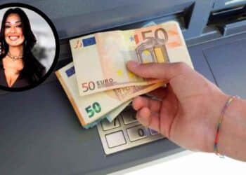 Mano sacando billetes de 50 € de un cajero automático con retrato de una notaria, concepto de riesgos fiscales por herencia.