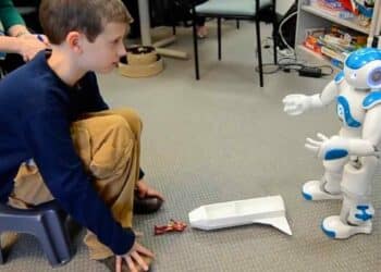 Intervención de robótica social en aula madrileña: niño con autismo y daño cerebral interactúa con el robot Robic para mejorar habilidades.