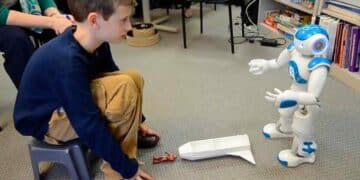 Intervención de robótica social en aula madrileña: niño con autismo y daño cerebral interactúa con el robot Robic para mejorar habilidades.