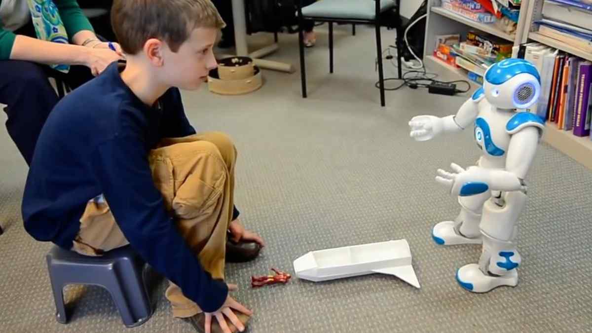 Intervención de robótica social en aula madrileña: niño con autismo y daño cerebral interactúa con el robot Robic para mejorar habilidades.