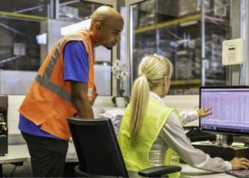 Trabajadores de almacén gestionan inventario en ordenador; sector logístico ofrece cinco ofertas de empleo con sueldos de hasta 30.000 euros.