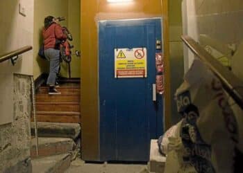 Mujer subiendo escaleras junto al ascensor en comunidad de vecinos tras sentencia del Tribunal Supremo
