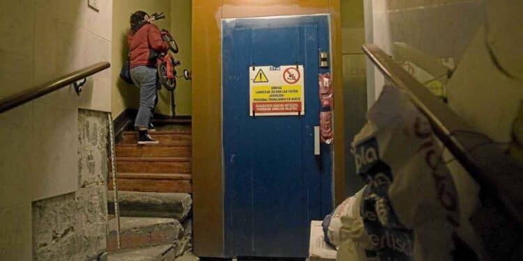 Mujer subiendo escaleras junto al ascensor en comunidad de vecinos tras sentencia del Tribunal Supremo