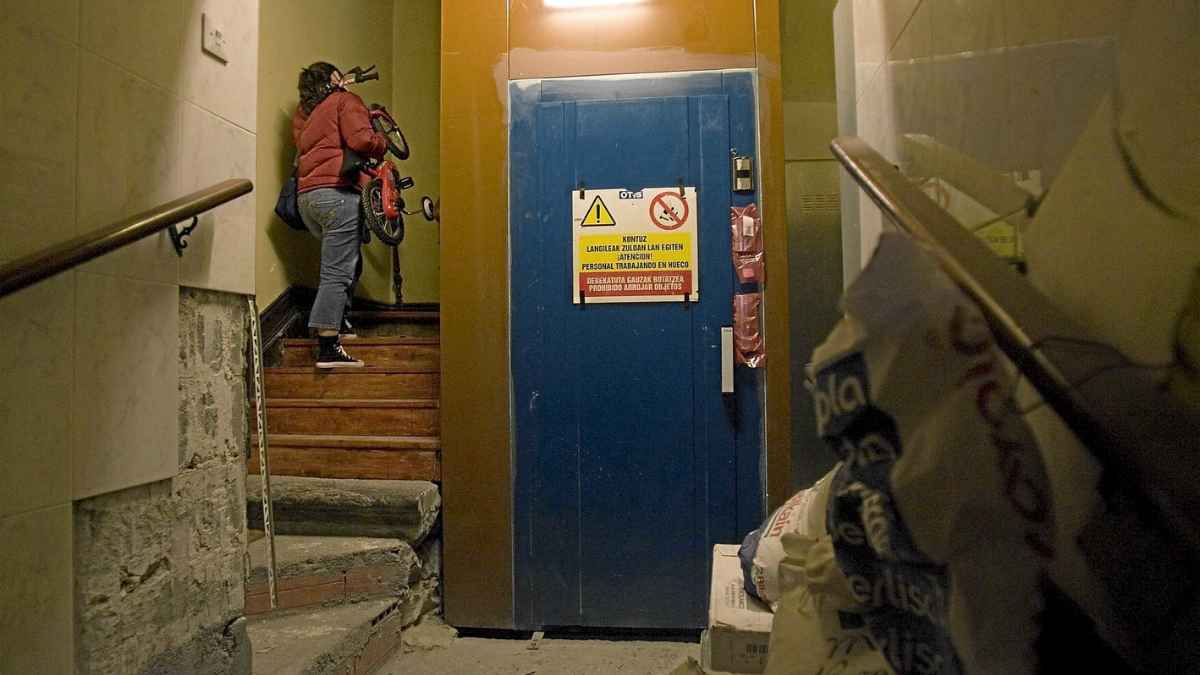 Mujer subiendo escaleras junto al ascensor en comunidad de vecinos tras sentencia del Tribunal Supremo
