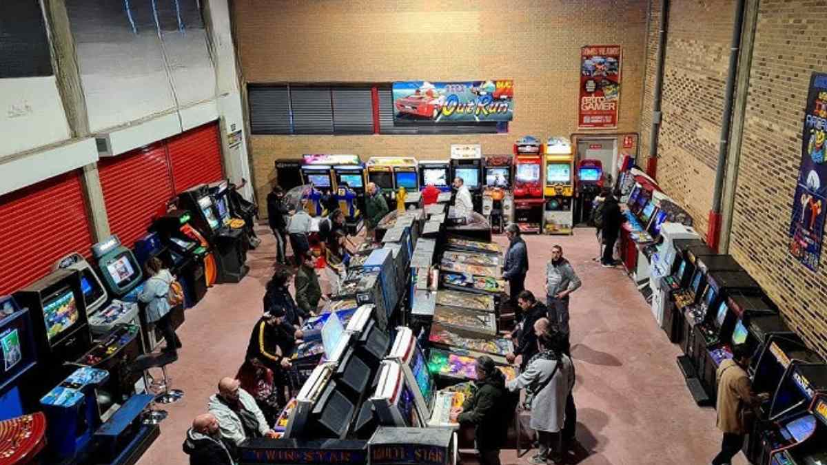interior del Templo del Arcade en Madrid con filas de máquinas recreativas retro y visitantes jugando.