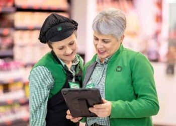 Trabajadoras de Mercadona consultan una tablet en tienda tras sentencia del TSJA sobre despido improcedente y humillaciones.