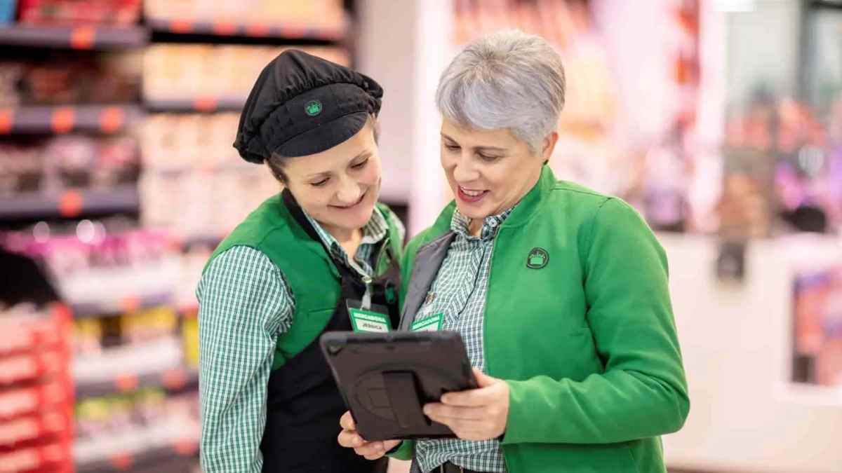 Trabajadoras de Mercadona consultan una tablet en tienda tras sentencia del TSJA sobre despido improcedente y humillaciones.
