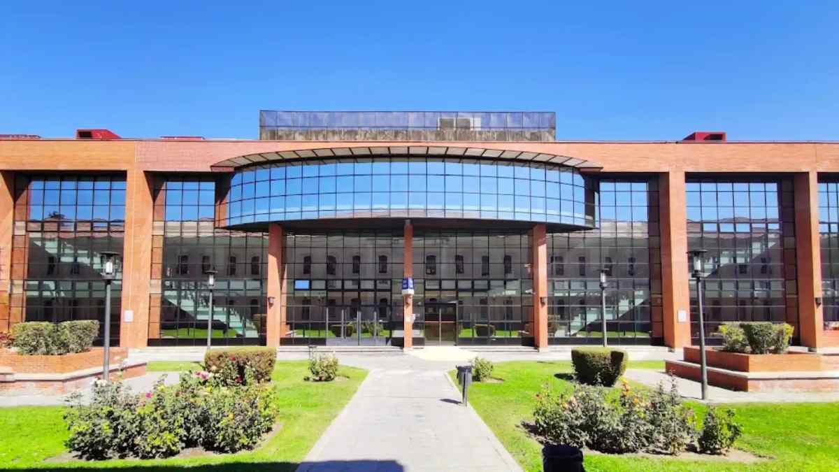 Fachada acristalada de una universidad pública madrileña con jardines, referente de los créditos más caros en España.