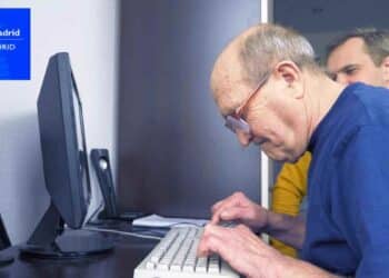Persona mayor usando ordenador para acceder a servicios sociales en Madrid.