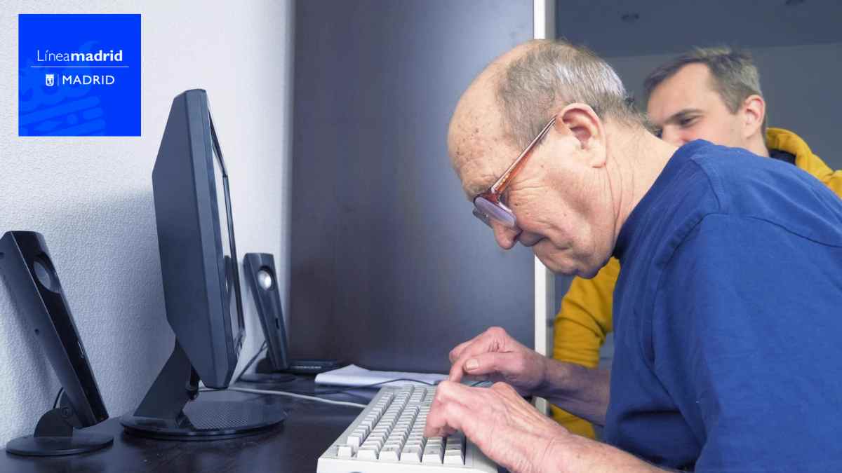 Persona mayor usando ordenador para acceder a servicios sociales en Madrid.