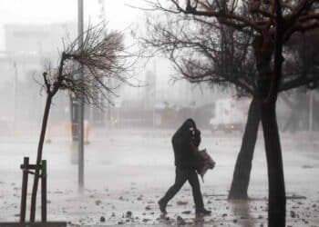 hombre caminando bajo tormenta en madrid con viento fuerte y lluvia.