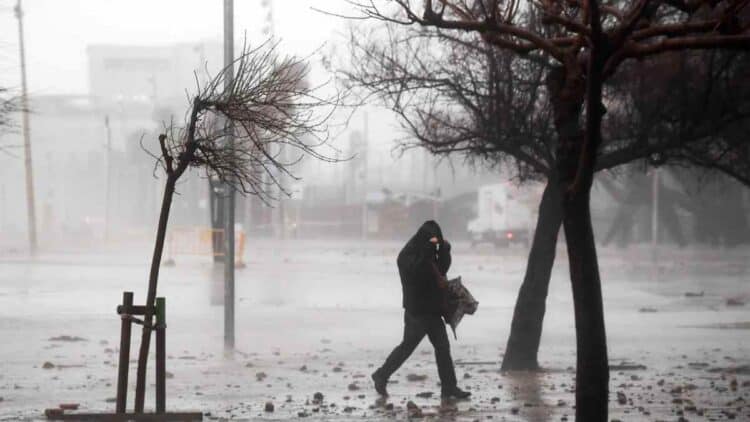 hombre caminando bajo tormenta en madrid con viento fuerte y lluvia.