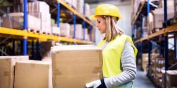 Trabajadora en almacén con caja en ofertas de empleo de la Agencia para el Empleo de Madrid.