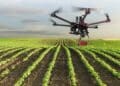 Dron agrícola sobrevolando cultivo en Madrid para vigilar cosechas y permitir el teletrabajo rural.