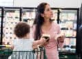 Madre soltera con su hijo en supermercado pensando en ayudas del SEPE y la Seguridad Social 2025.