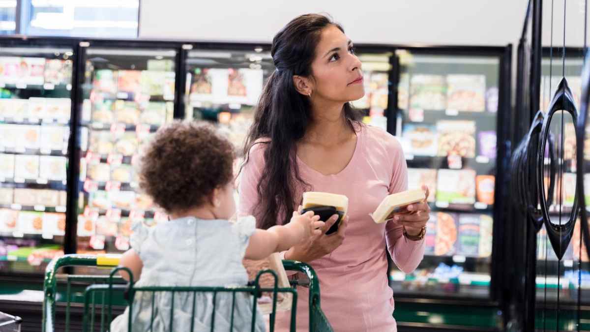Madre soltera con su hijo en supermercado pensando en ayudas del SEPE y la Seguridad Social 2025.