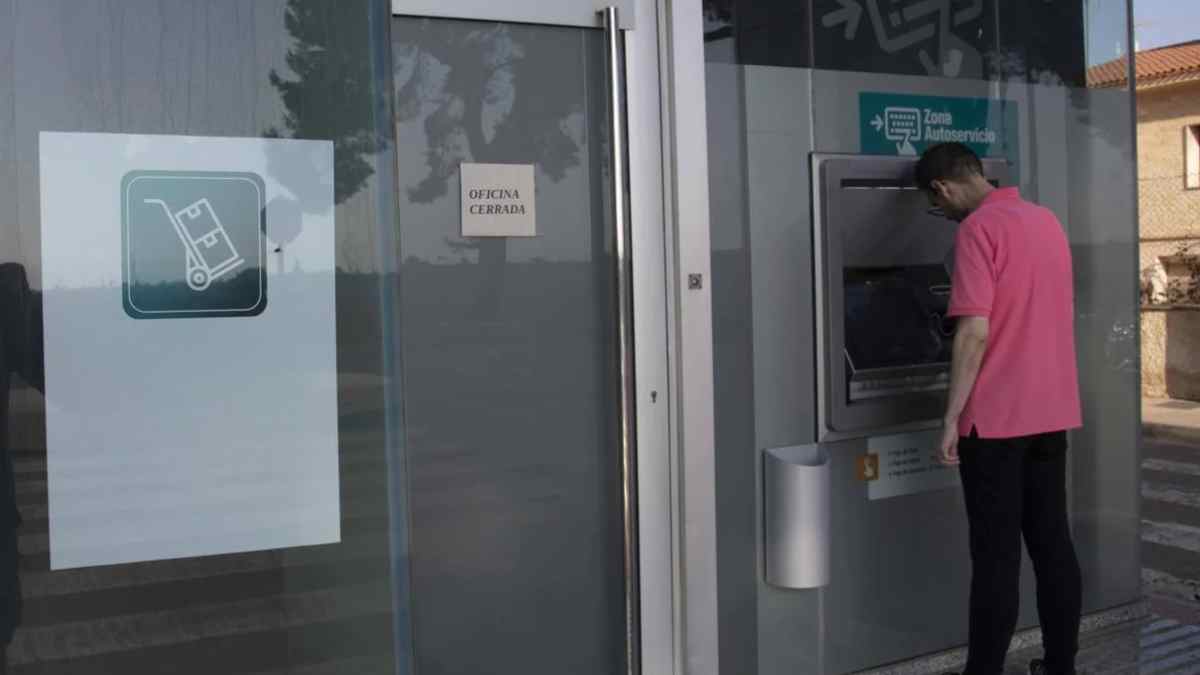 Hombre usando cajero automático con sucursal bancaria cerrada por festivo del 15 de agosto.