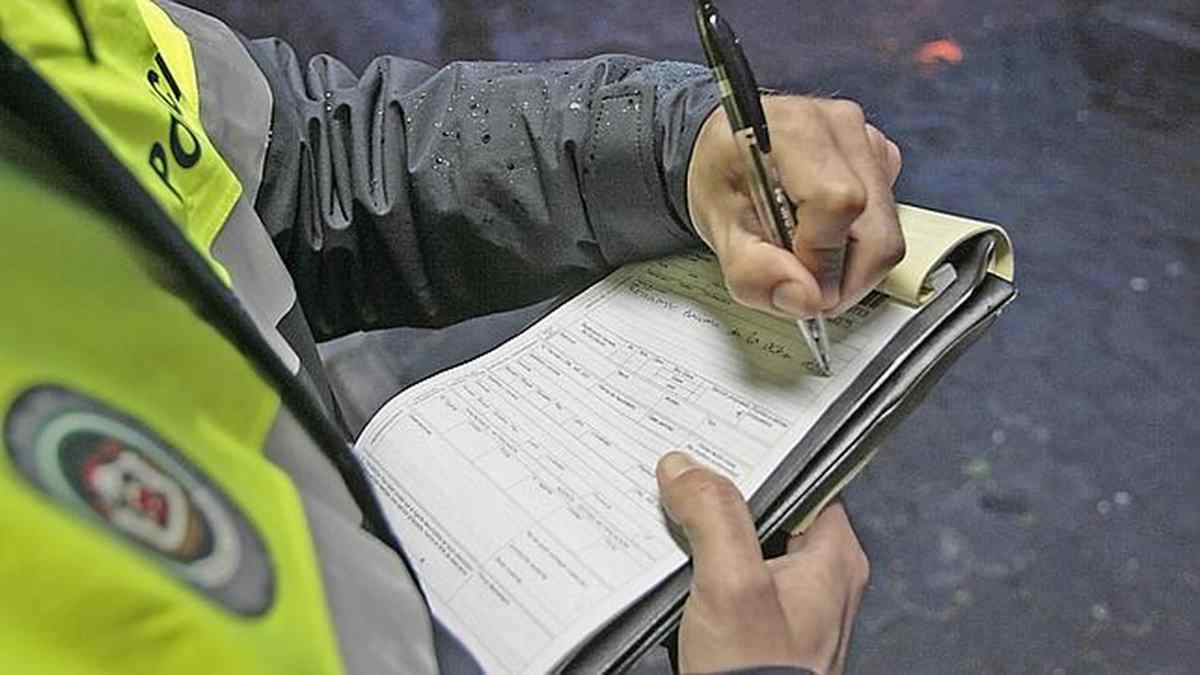 Policía rellenando multa de tráfico por no llevar carné de conducir.