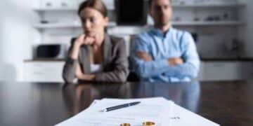 Pareja en proceso de divorcio con documentos y anillos sobre la mesa.