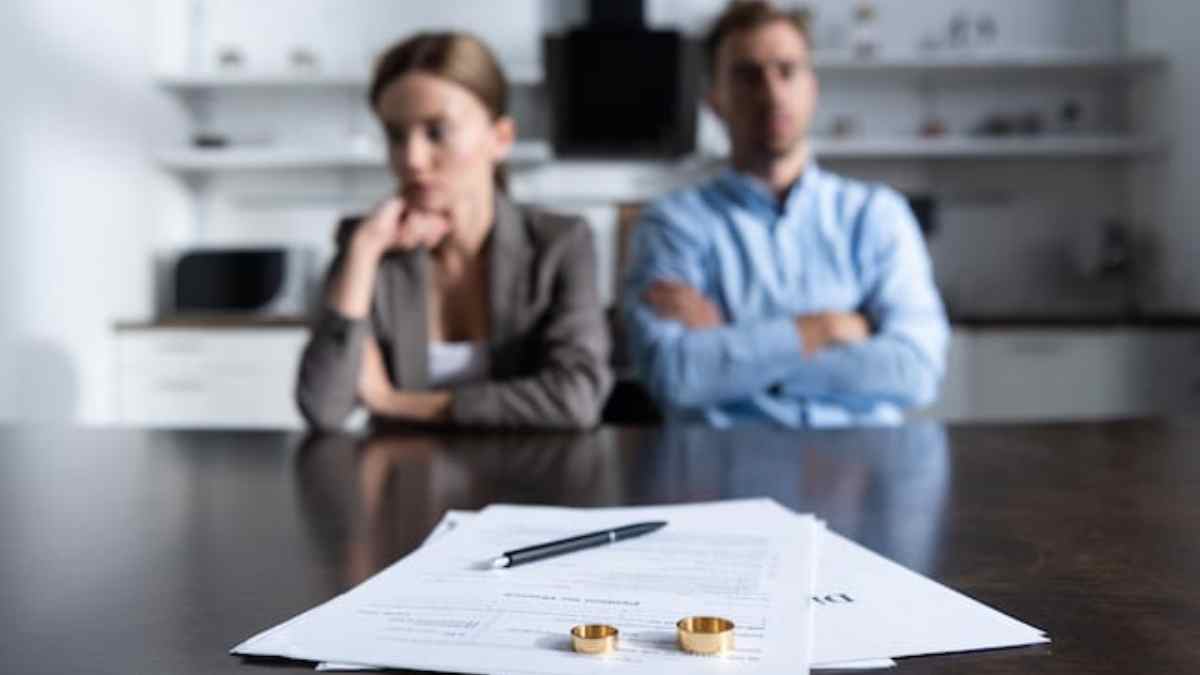 Pareja en proceso de divorcio con documentos y anillos sobre la mesa.