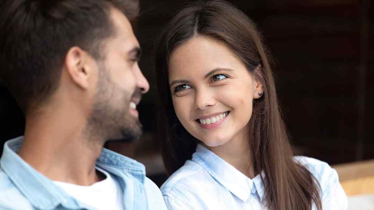 Mujer sonríe mirando a un hombre como gesto que delata atracción según la ciencia.