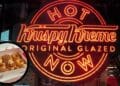Letrero Hot Now de Krispy Kreme y caja de dónuts glaseados en Madrid.