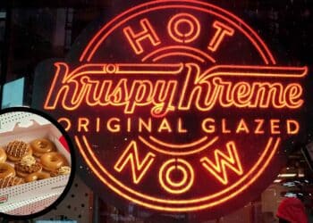 Letrero Hot Now de Krispy Kreme y caja de dónuts glaseados en Madrid.
