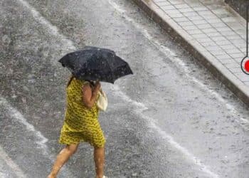 Mujer con paraguas bajo tormenta en Madrid tras ola de calor de 41 grados.