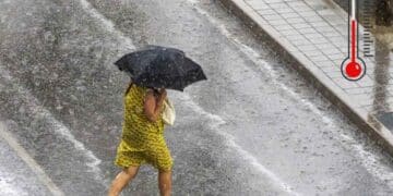 Mujer con paraguas bajo tormenta en Madrid tras ola de calor de 41 grados.