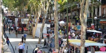 Mercadillo en Madrid con puestos de ropa y artesanía al aire libre.