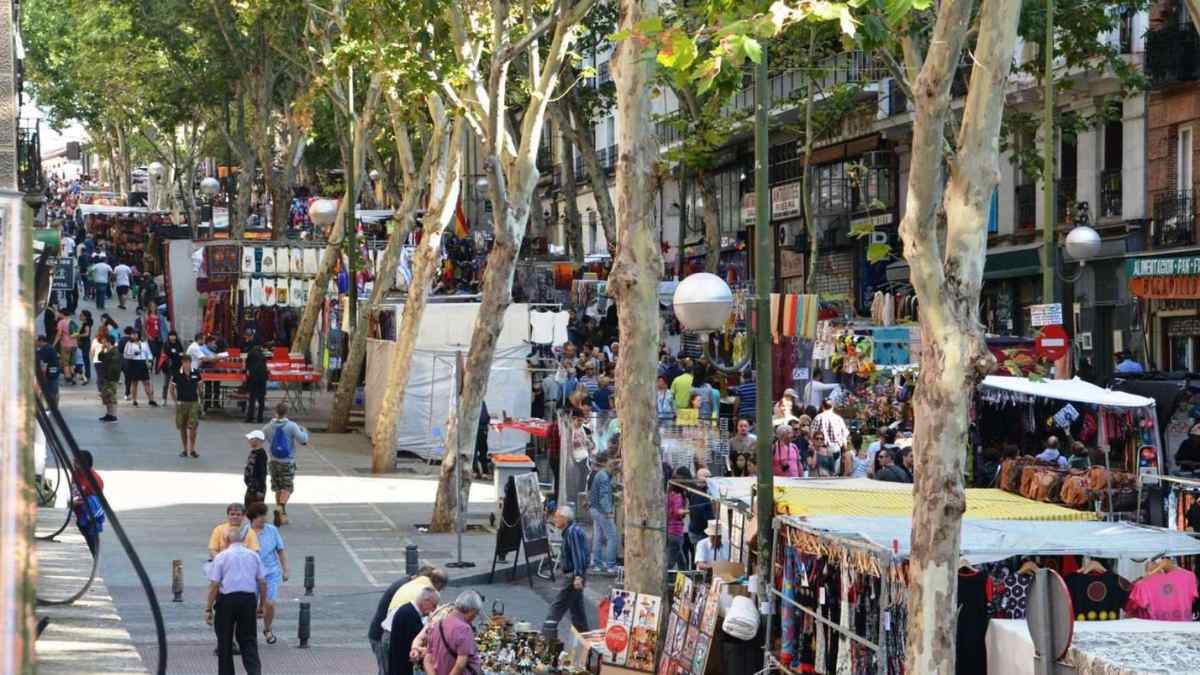 Mercadillo en Madrid con puestos de ropa y artesanía al aire libre.