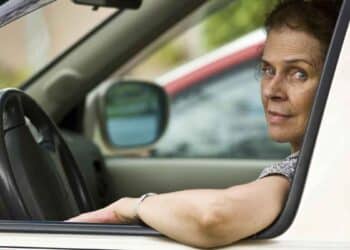 Mujer conduciendo con el brazo apoyado en la ventanilla del coche.