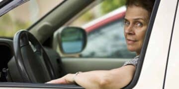 Mujer conduciendo con el brazo apoyado en la ventanilla del coche.