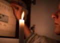 Mujer con vela durante corte de luz en Madrid por apagones programados.