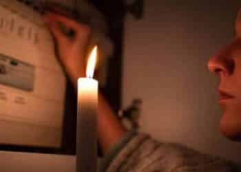 Mujer con vela durante corte de luz en Madrid por apagones programados.