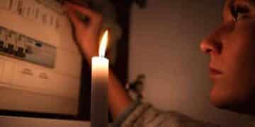 Mujer con vela durante corte de luz en Madrid por apagones programados.