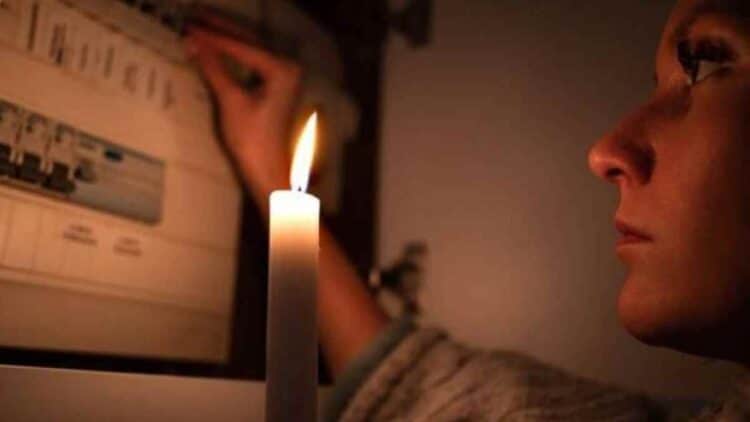 Mujer con vela durante corte de luz en Madrid por apagones programados.