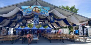 Carpa bávara de la Oktoberfest en Vallecas Madrid con mesas de madera y decoración alemana.
