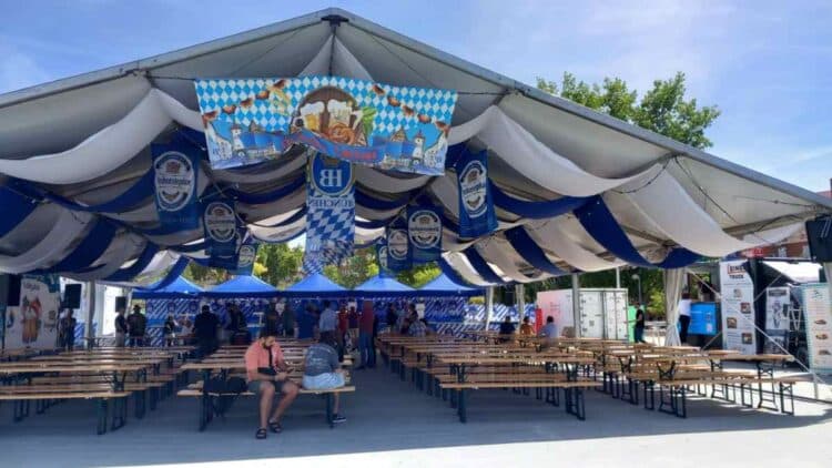 Carpa bávara de la Oktoberfest en Vallecas Madrid con mesas de madera y decoración alemana.