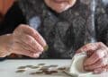Mujer mayor contando monedas para su pensión en 2025 con 15 años cotizados.