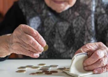 Mujer mayor contando monedas para su pensión en 2025 con 15 años cotizados.