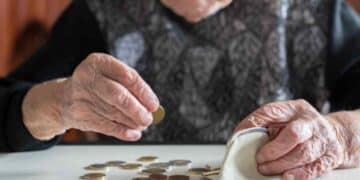 Mujer mayor contando monedas para su pensión en 2025 con 15 años cotizados.