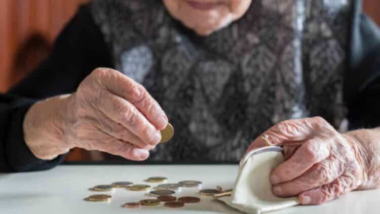 Mujer mayor contando monedas para su pensión en 2025 con 15 años cotizados.