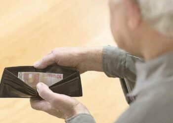 Hombre mayor revisando cartera con poco dinero por devolver IMV.
