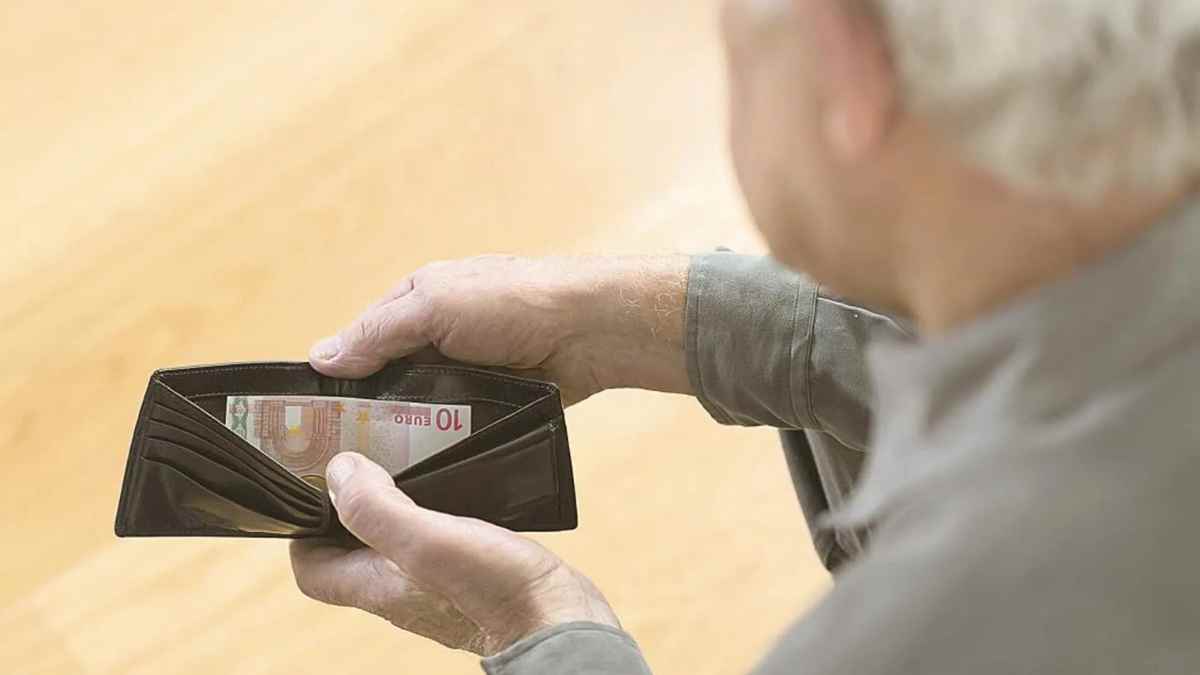 Hombre mayor revisando cartera con poco dinero por devolver IMV.