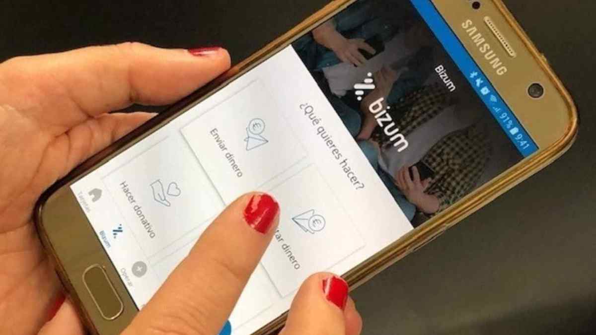 Persona usando la app de Bizum en el móvil, relacionada con el timo del Bizum inverso en compraventa.