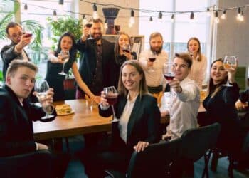 Trabajadores en fiesta de empresa con copas de vino y alcohol.